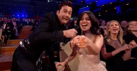 David Tennant and Camila Cabello in the audience at the Bafta Film Awards, with Tennant holding up a mic as Cabello sings