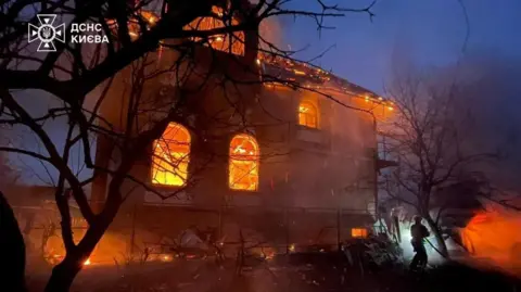 Reuters A firefighter works at a residential building that is ablaze