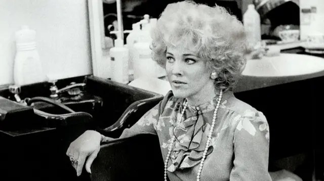 A black and white photo showing Catherine O'Hara in costume behind the scenes of SCTV